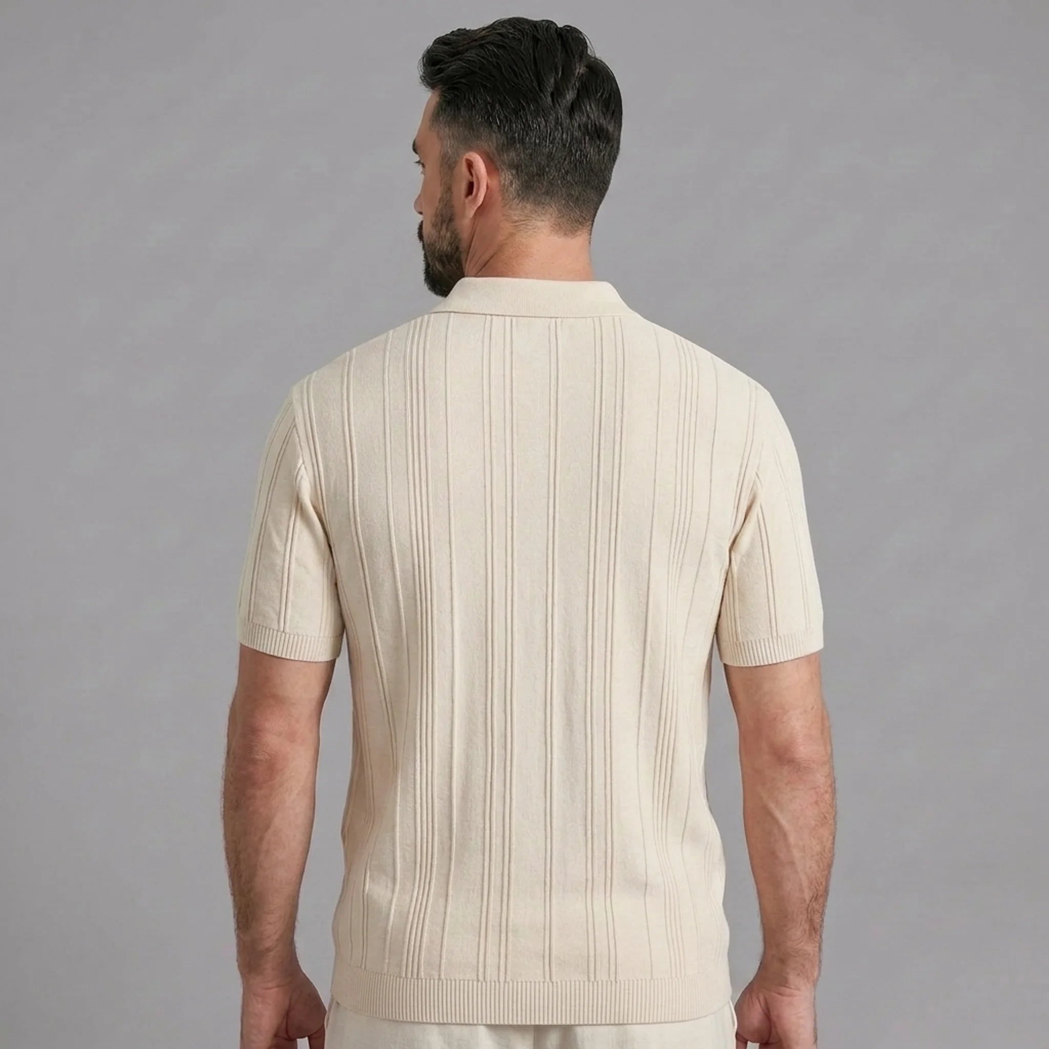 Side view of man in beige stripe jacquard knit zip-up polo shirt on plain background