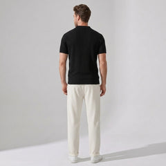 Man wearing beige striped knit polo and waffle pants walking in outdoor lifestyle setting