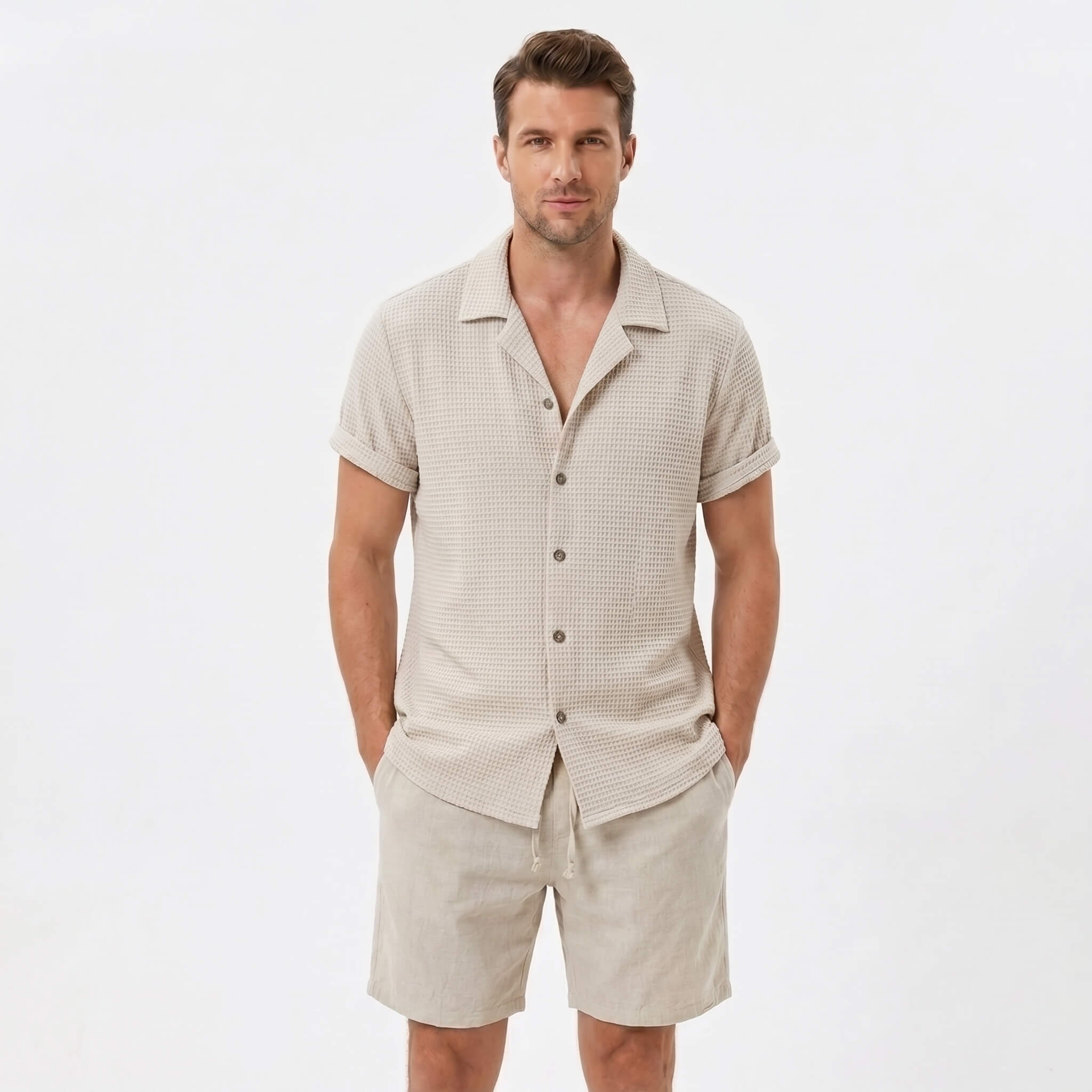 Man wearing a beige textured Cuban shirt and linen cotton drawstring shorts front view on plain background