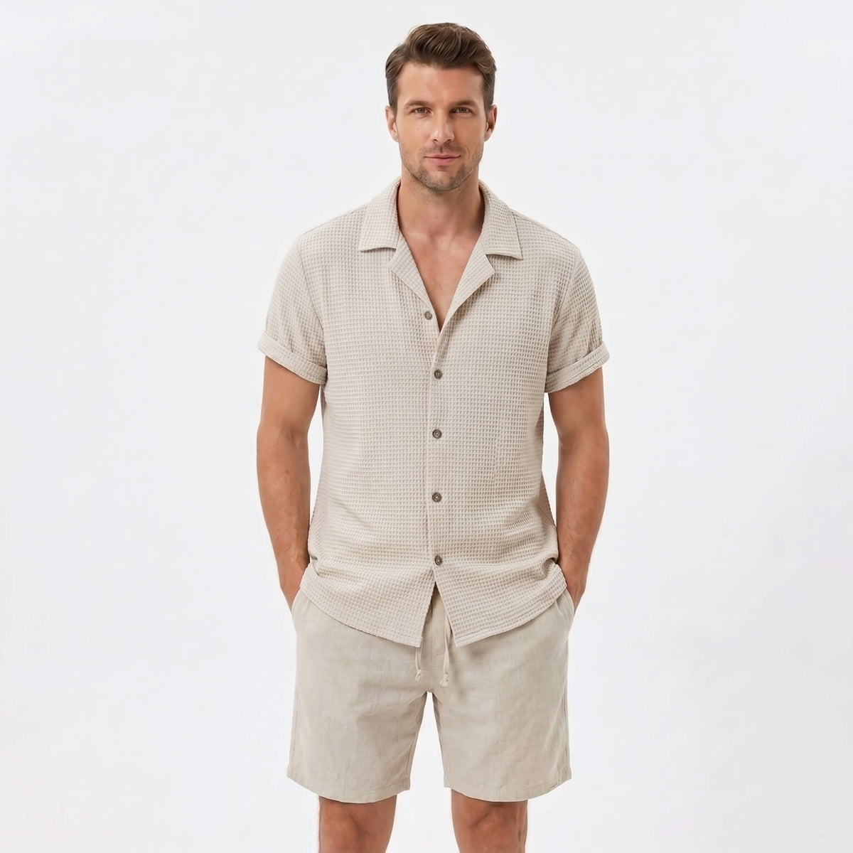 Man wearing a beige textured Cuban shirt and linen cotton drawstring shorts front view on plain background