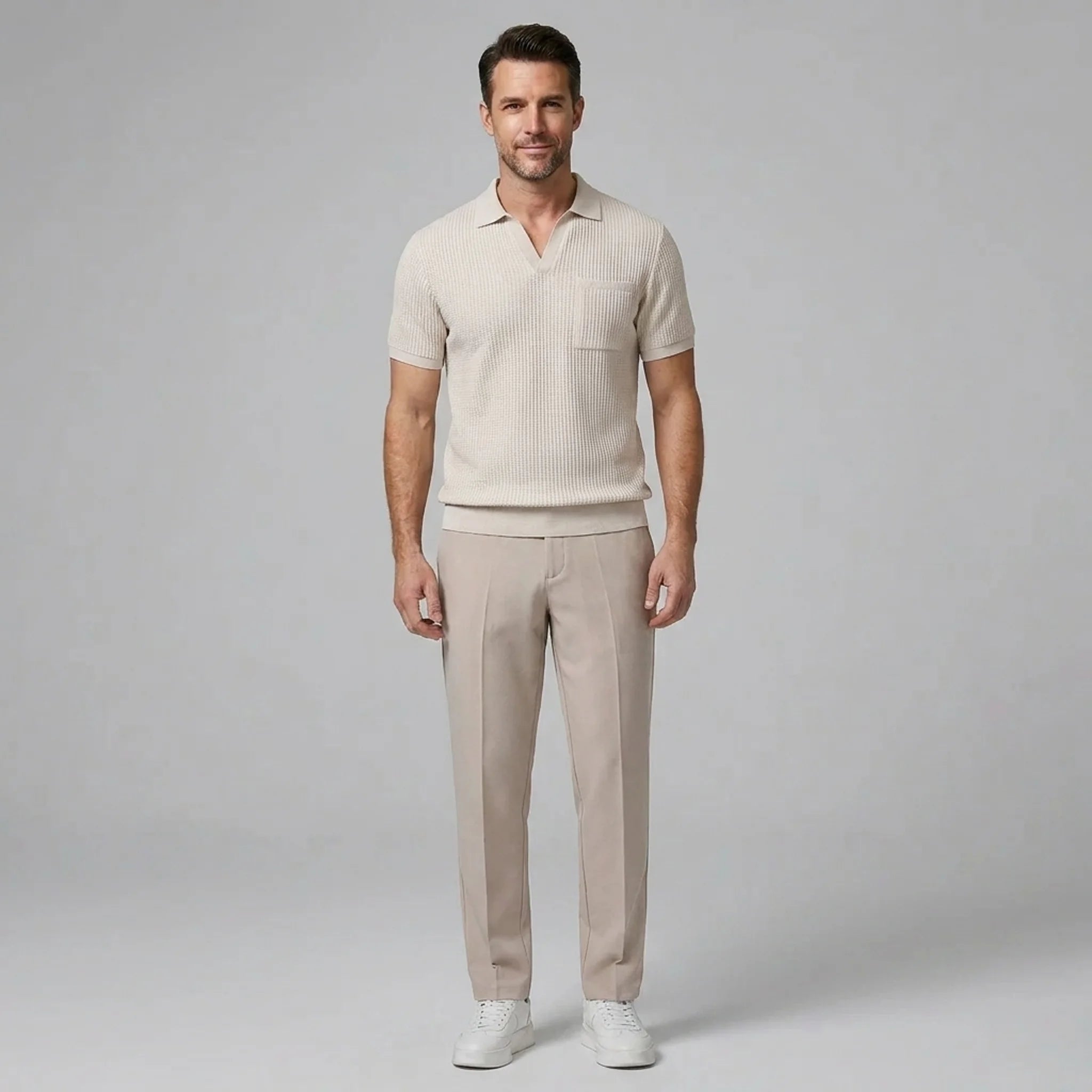 Man wearing a beige waffle johnny collar polo shirt and slim fit tapered pants front view on plain background