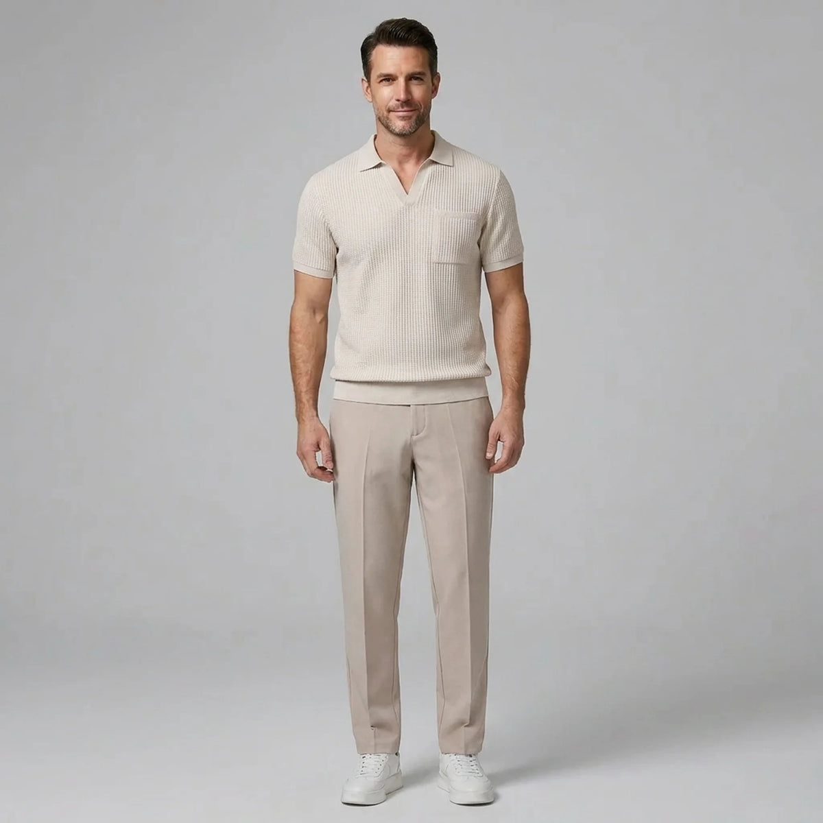 Man wearing a beige waffle johnny collar polo shirt and slim fit tapered pants front view on plain background