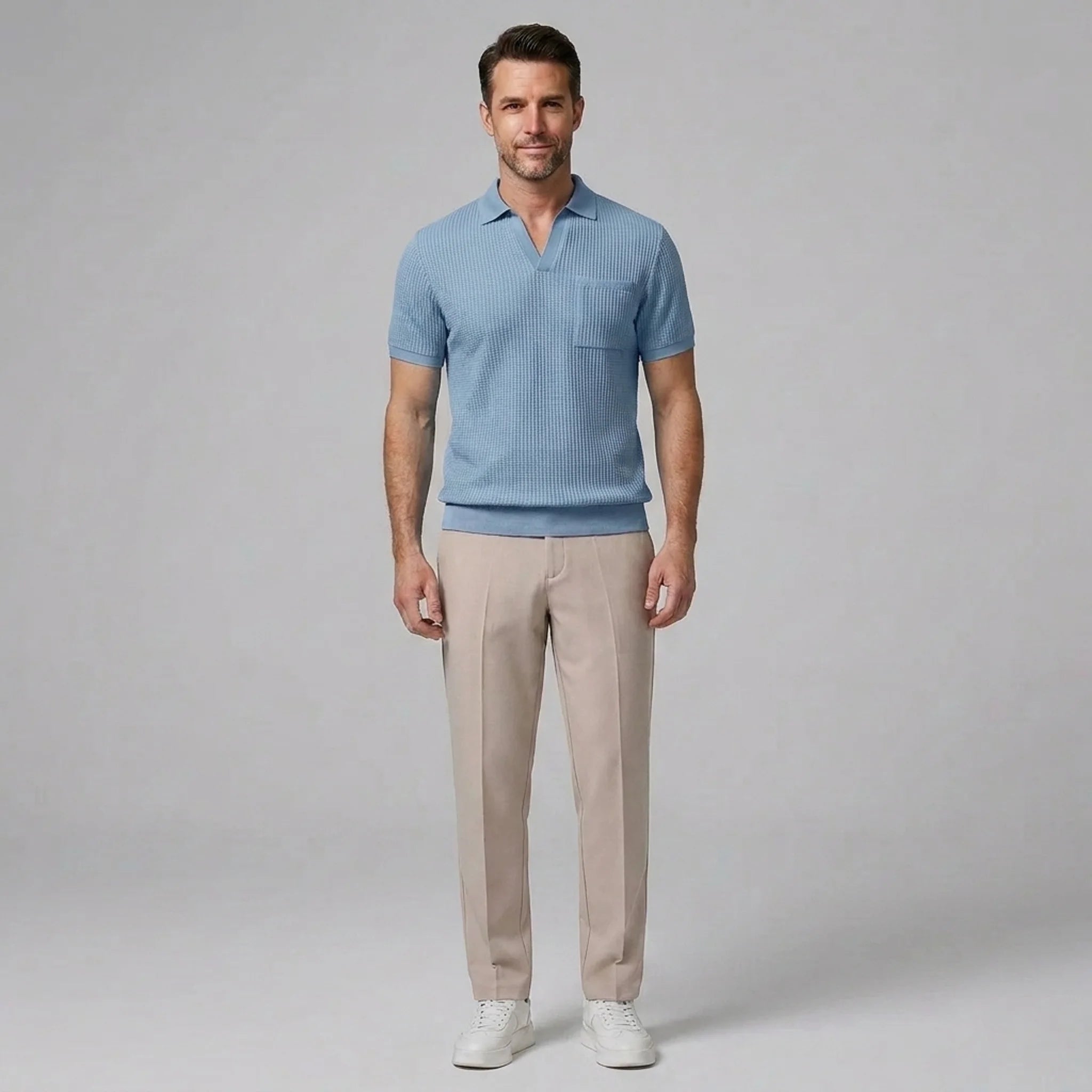 Man in beige waffle johnny collar polo and tapered pants walking in sunny outdoor summer scene