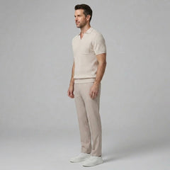 Side view of man in beige waffle johnny collar polo and slim fit tapered pants on plain background
