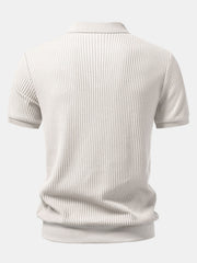 Man in beige waffle johnny collar polo and slim fit tapered pants in sunny outdoor scene