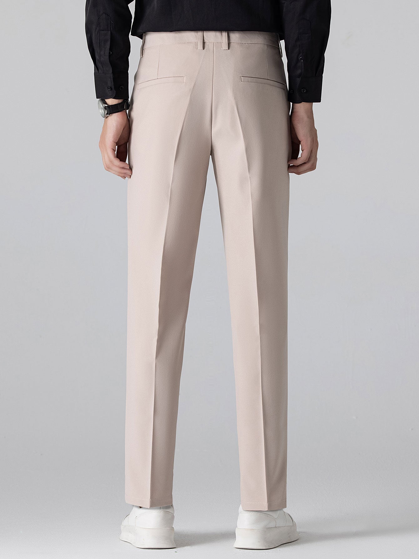 Man wearing beige waffle polo and tapered pants three quarter view on plain background