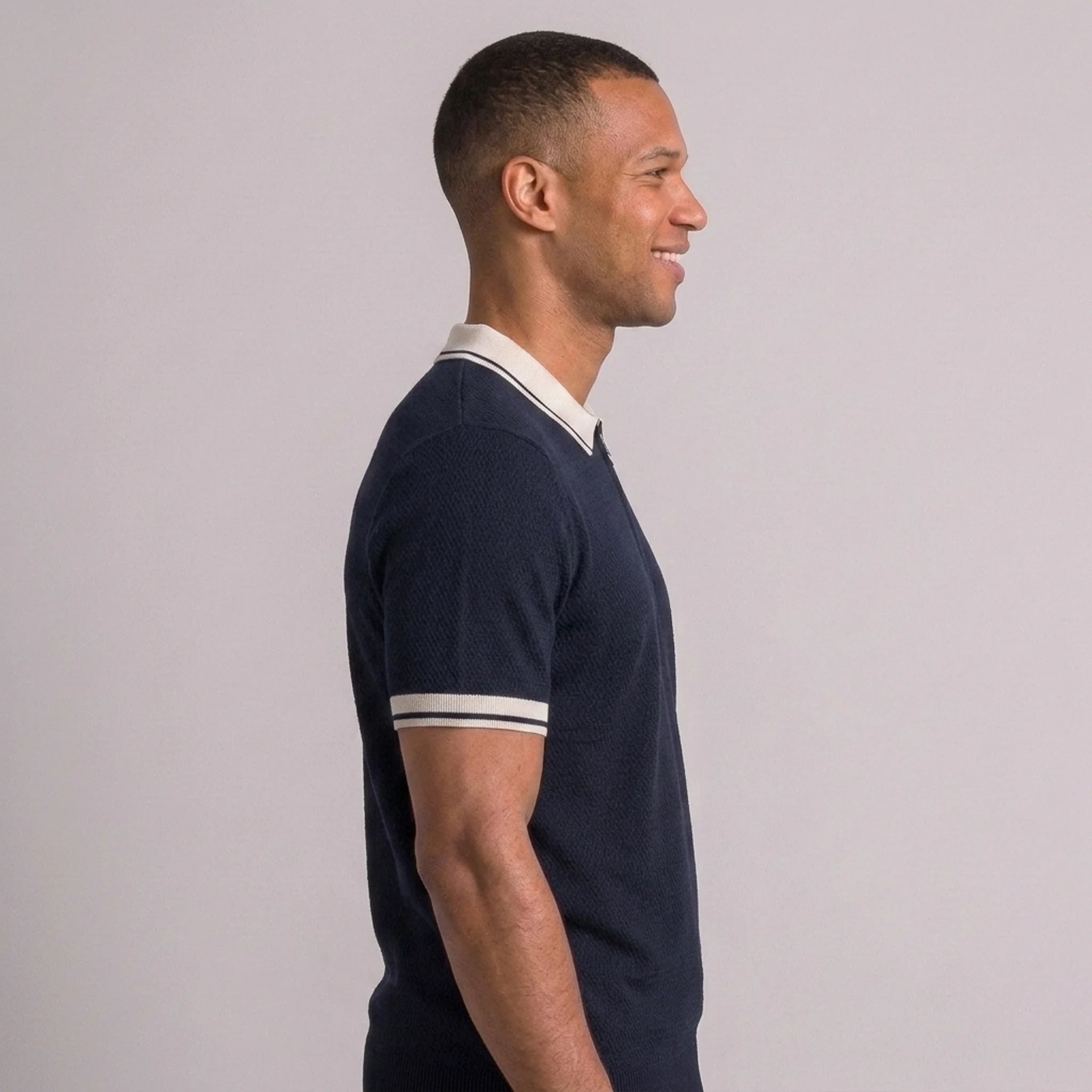 Back view of man wearing black color block knit polo shirt with lapel collar