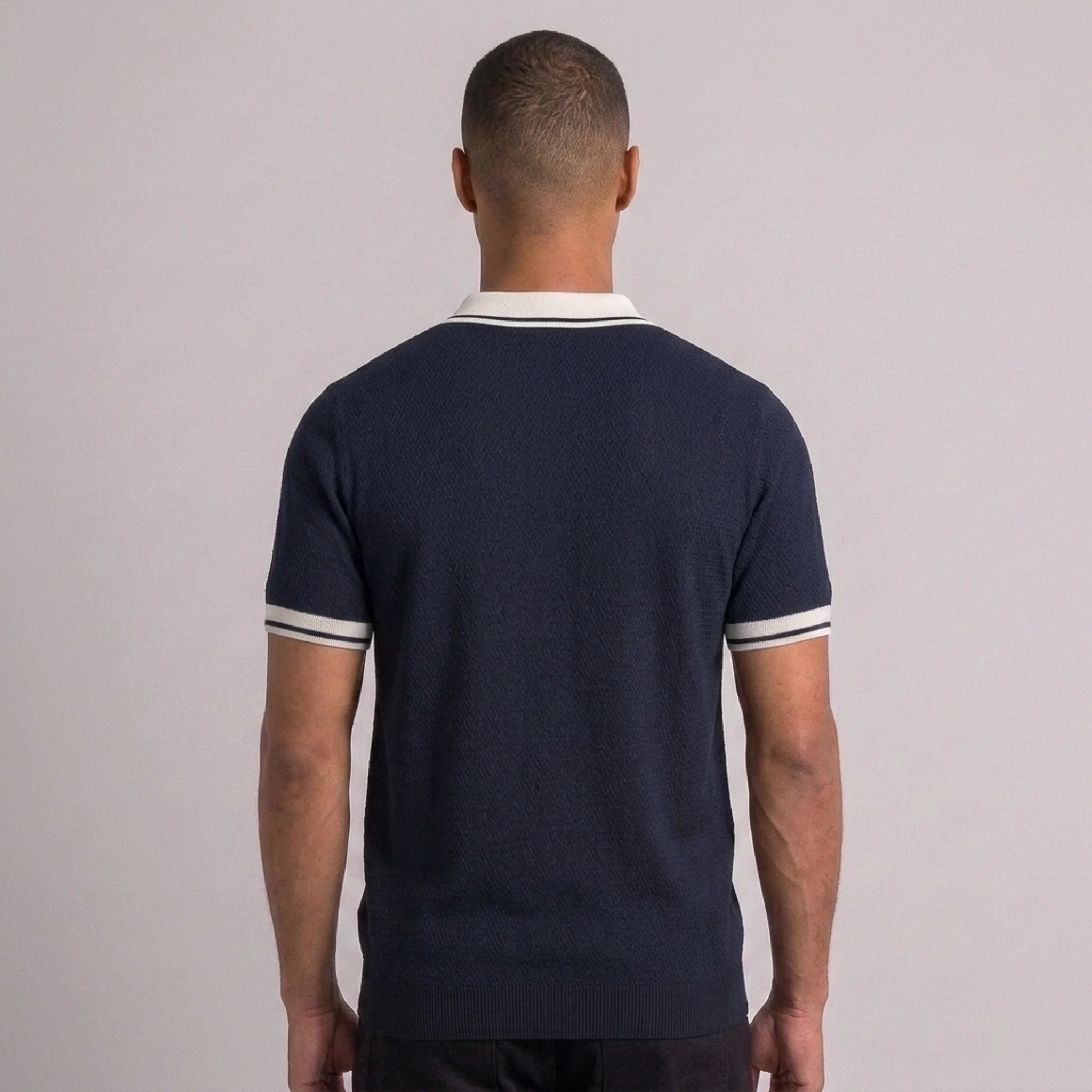 Man wearing black color block knit polo shirt in outdoor lifestyle setting