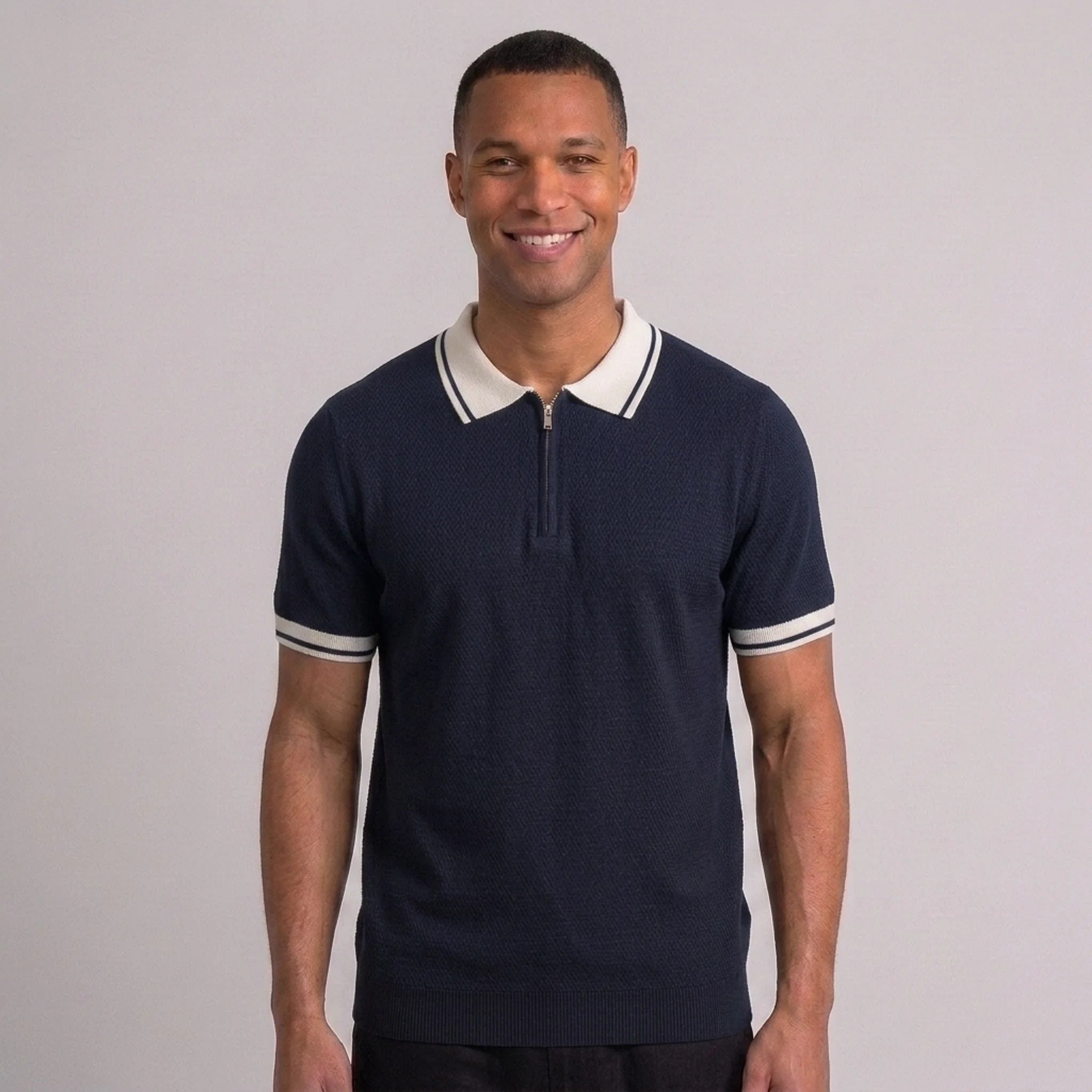 Side view of man in black color block knit polo shirt with lapel collar