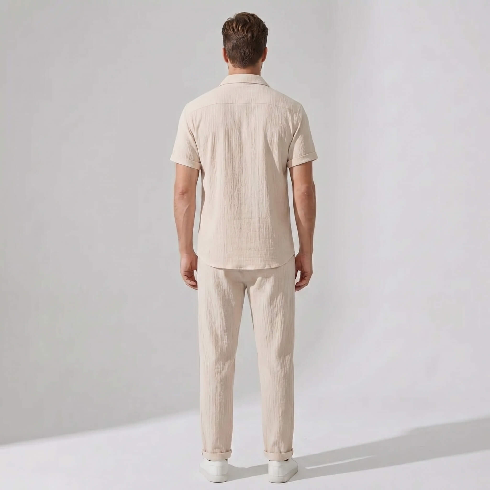Back view of man wearing black crinkled textured button up shirt and straight leg pants