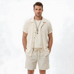 Back view of man wearing black floral checkerboard jacquard Cuban shirt and linen drawstring shorts