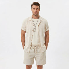 Back view of man wearing black floral checkerboard jacquard Cuban shirt and linen drawstring shorts
