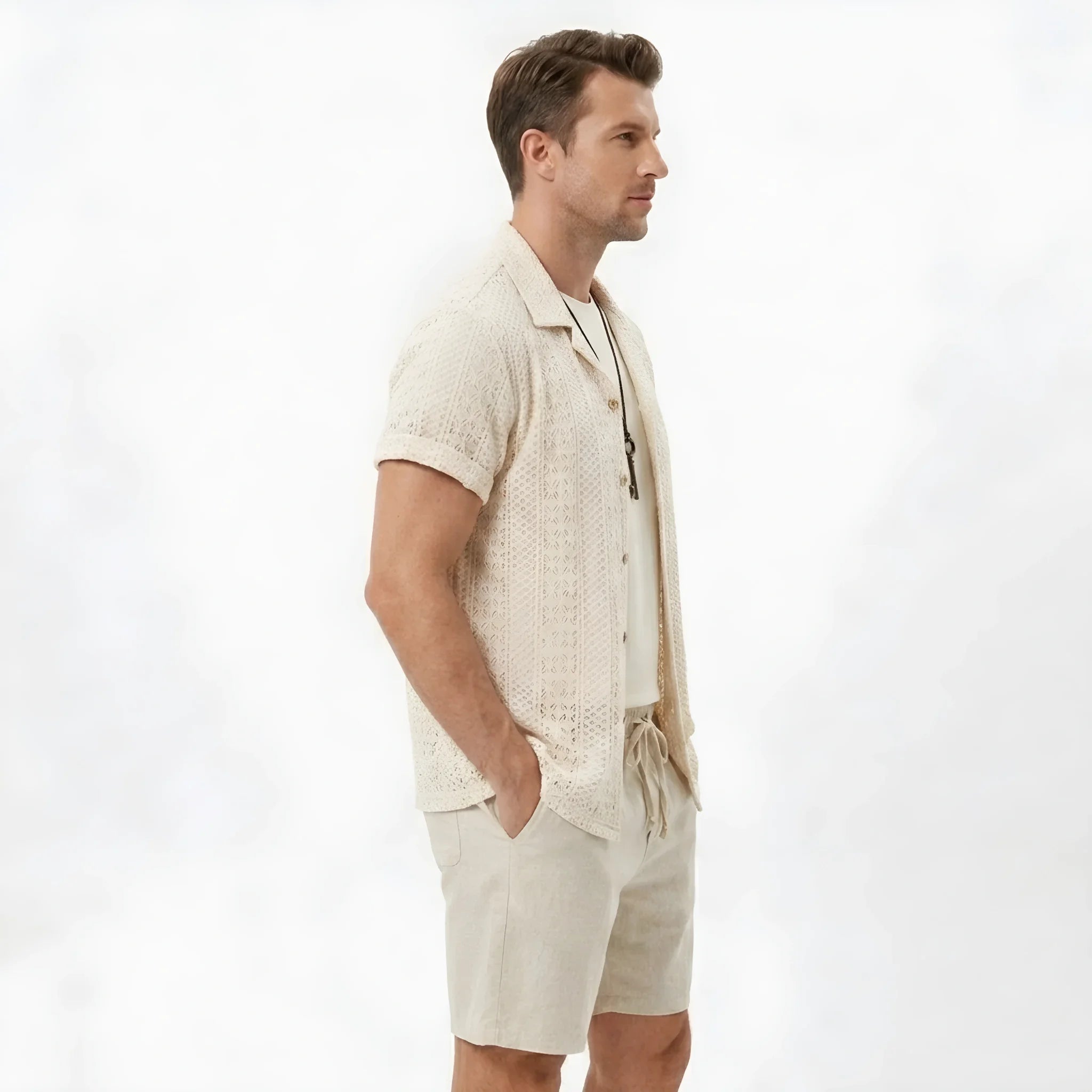 Side view of man in black floral checkerboard jacquard Cuban shirt and linen drawstring shorts