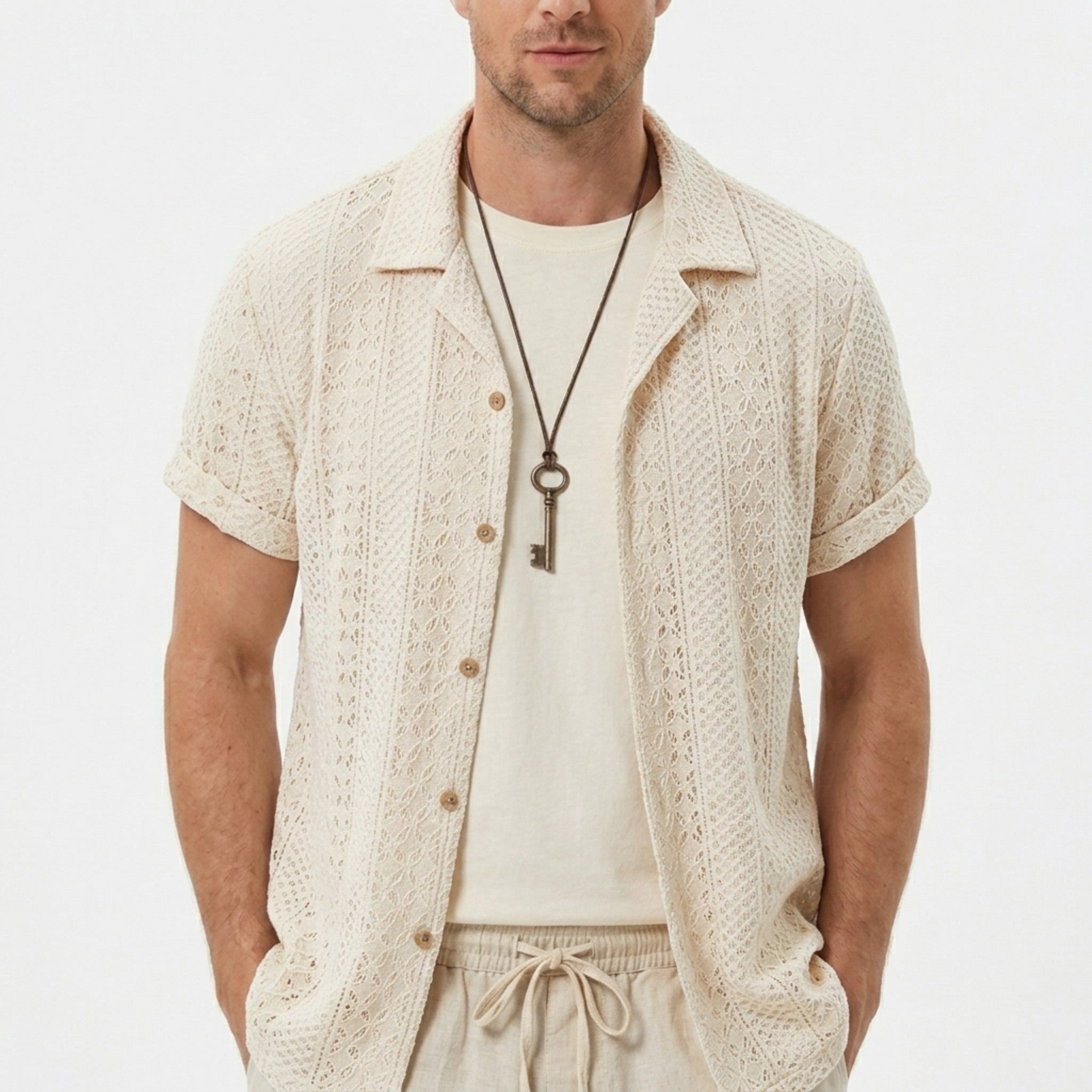 Three quarter view of man in black floral checkerboard jacquard Cuban shirt and drawstring shorts
