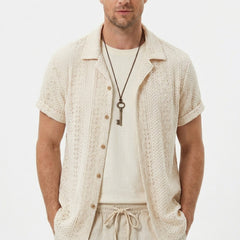 Three quarter view of man in black floral checkerboard jacquard Cuban shirt and drawstring shorts