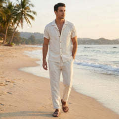 Side view of man in black floral checkerboard jacquard Cuban shirt and straight leg linen pants