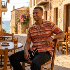 Man wearing black geometric Cuban shirt and linen pants in resort outdoor lifestyle scene