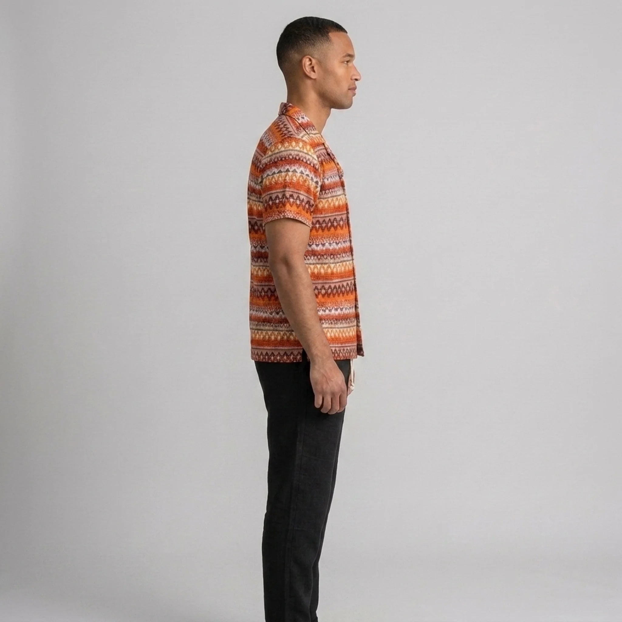Back view of man wearing black geometric Cuban shirt and straight leg linen pants