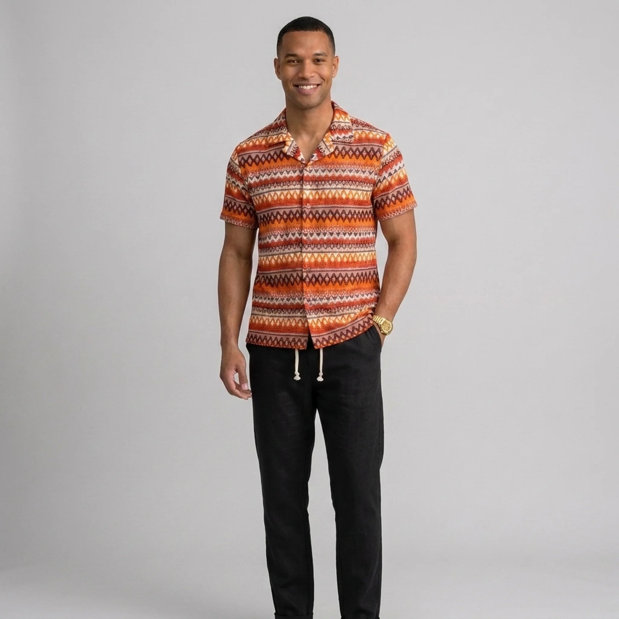 Man wearing a black geometric Cuban shirt and straight leg linen pants front view on plain background