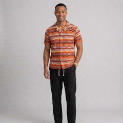 Man wearing a black geometric Cuban shirt and straight leg linen pants front view on plain background