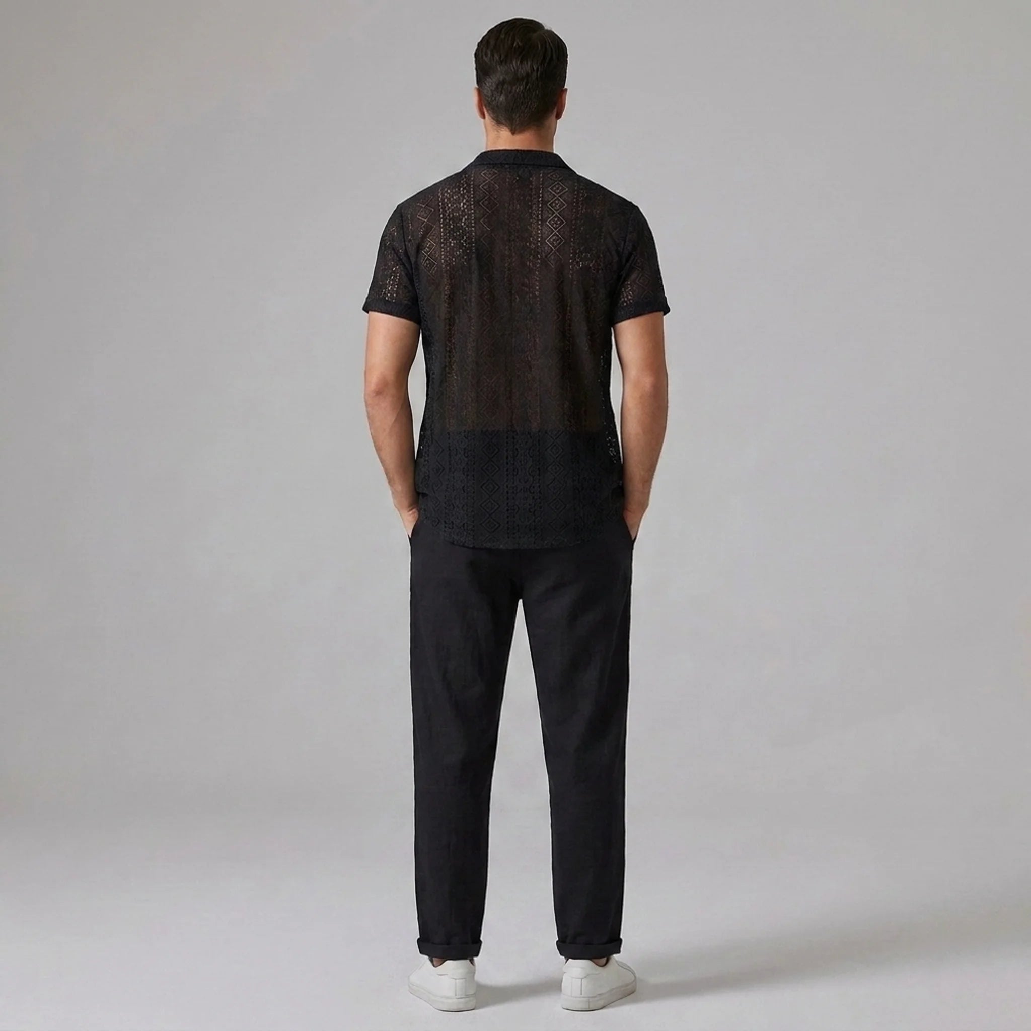 Back view of man wearing black geometry textured Cuban shirt and straight leg linen pants