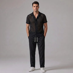 Man wearing black geometry textured Cuban shirt and straight leg linen pants front view on plain background