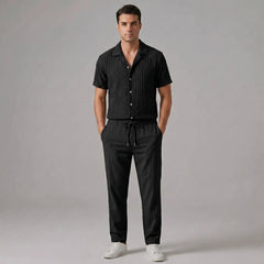 Man wearing black jacquard Cuban collar shirt and crinkle textured straight leg pants front view