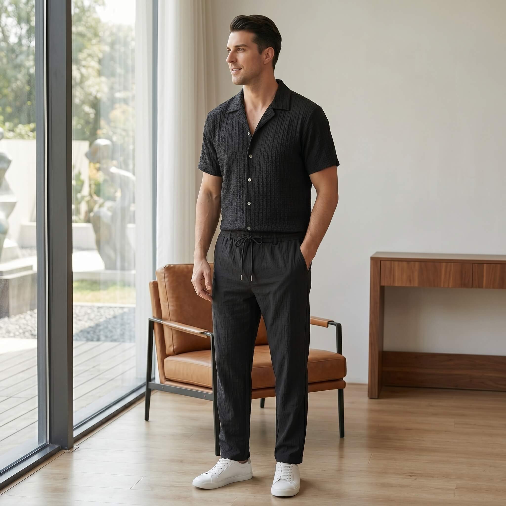 Man wearing black jacquard Cuban shirt and crinkle pants walking in sunny outdoor summer scene