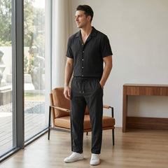 Man wearing black jacquard Cuban shirt and crinkle pants walking in sunny outdoor summer scene