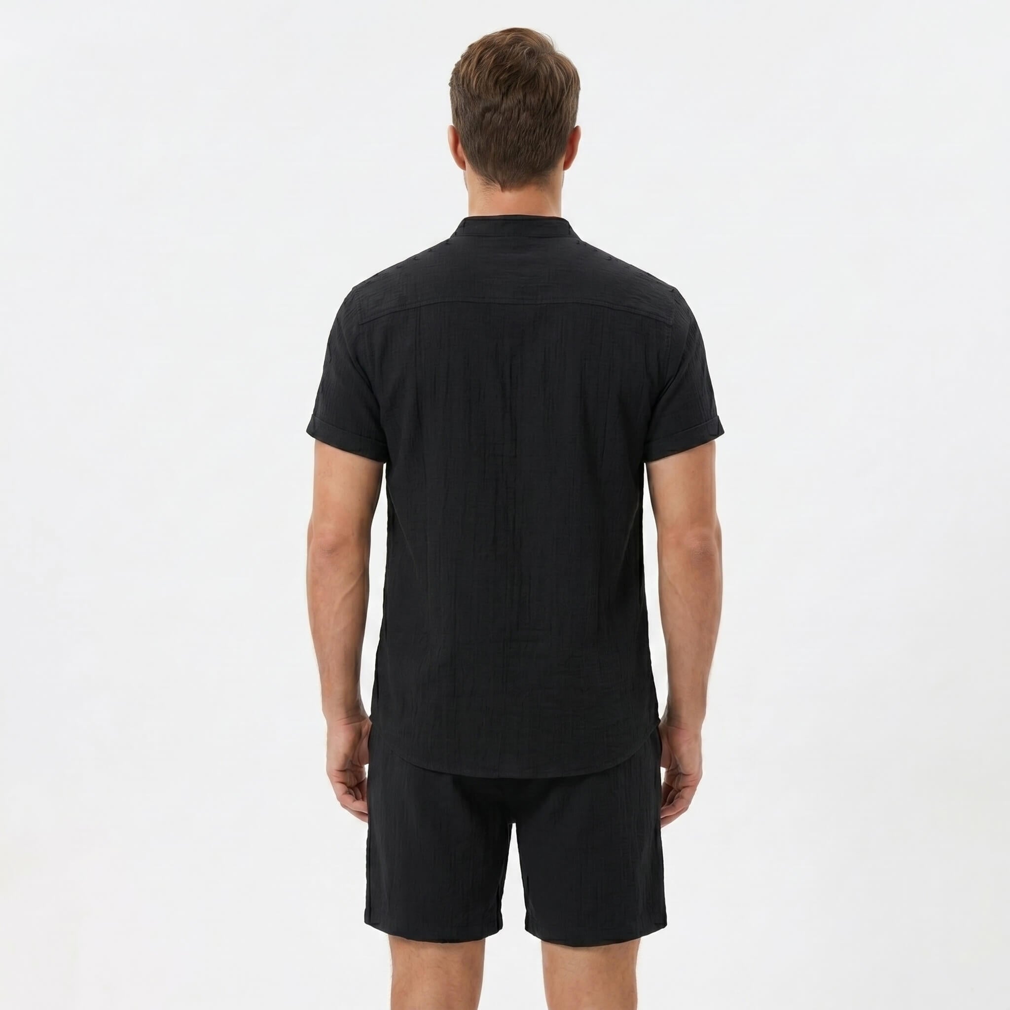Back view of man wearing black linen look stand collar shirt and crinkle drawstring shorts