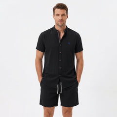 Man wearing a black linen look stand collar shirt and crinkle textured drawstring shorts front view