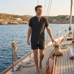 Man in black linen look stand collar shirt and crinkle drawstring shorts in sunny outdoor summer scene