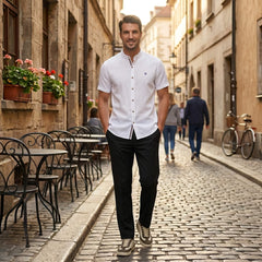Man wearing black linen look stand collar shirt and tapered trousers relaxing outdoors