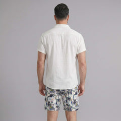 Back view of man wearing black linen rayon shirt and white palm tree print swim shorts