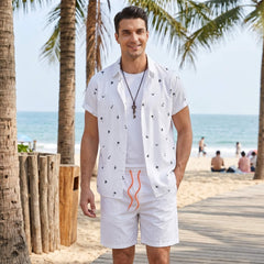 Man in black palm tree anchor sailboat print shirt and swim shorts in sunny outdoor beach scene