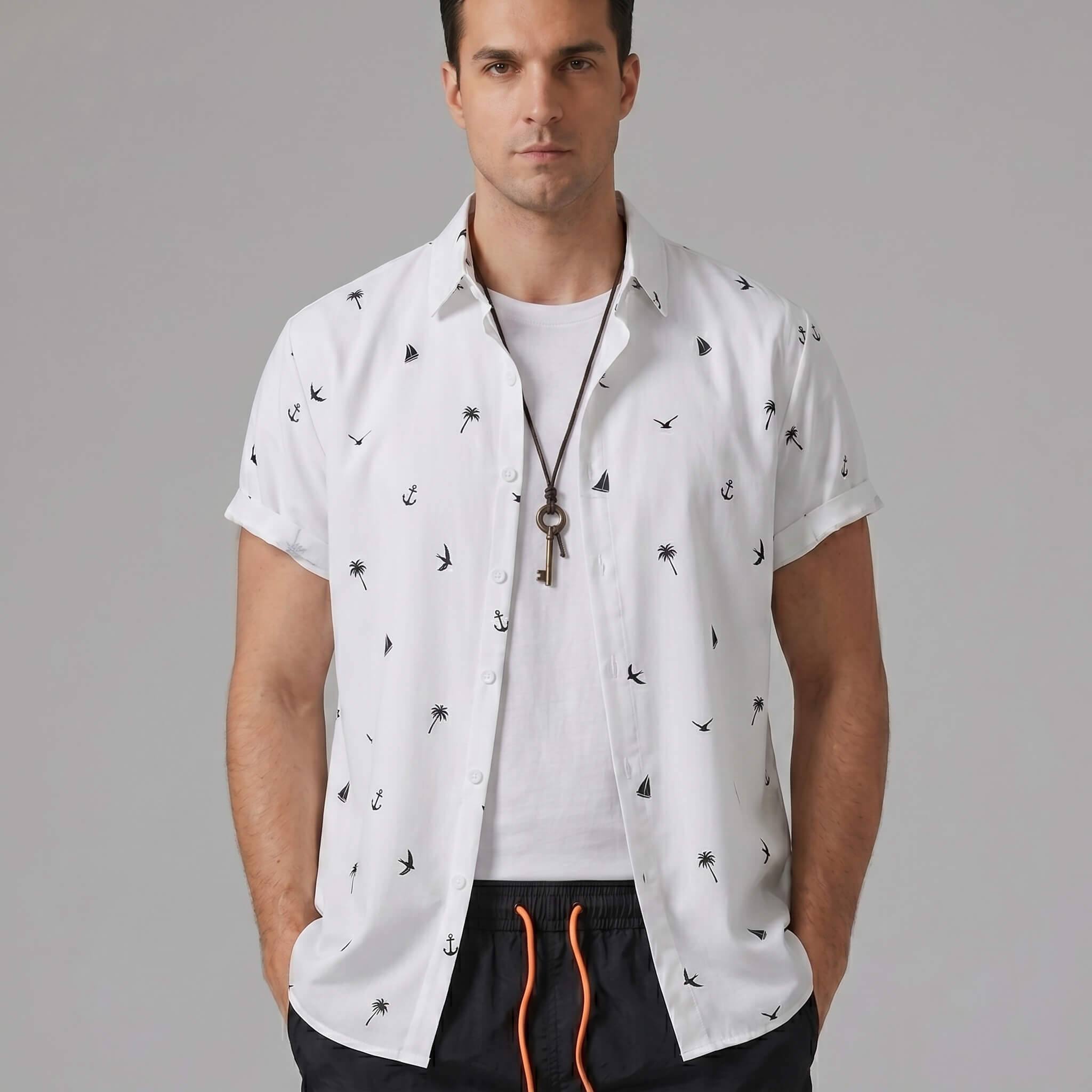 Three quarter view of man in black palm tree anchor sailboat print shirt and swim shorts