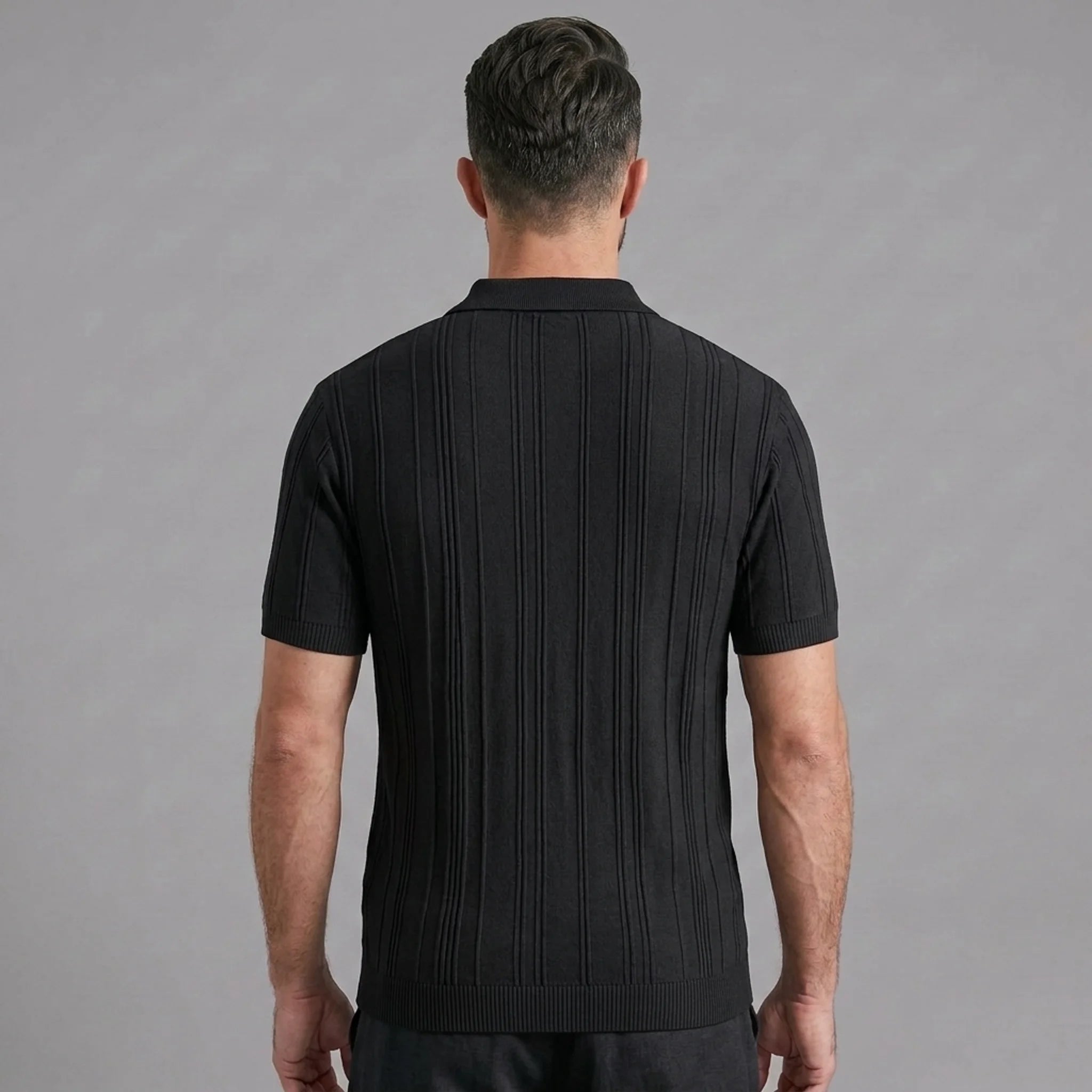 Side view of man in black stripe jacquard knit zip-up polo shirt on plain background