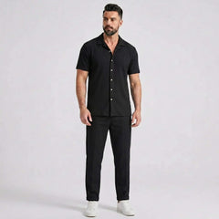 Man wearing a black waffle button up shirt and straight leg linen pants front view