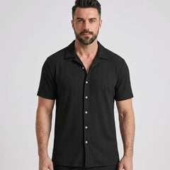 Three quarter view of man in black waffle button up shirt and straight leg linen pants