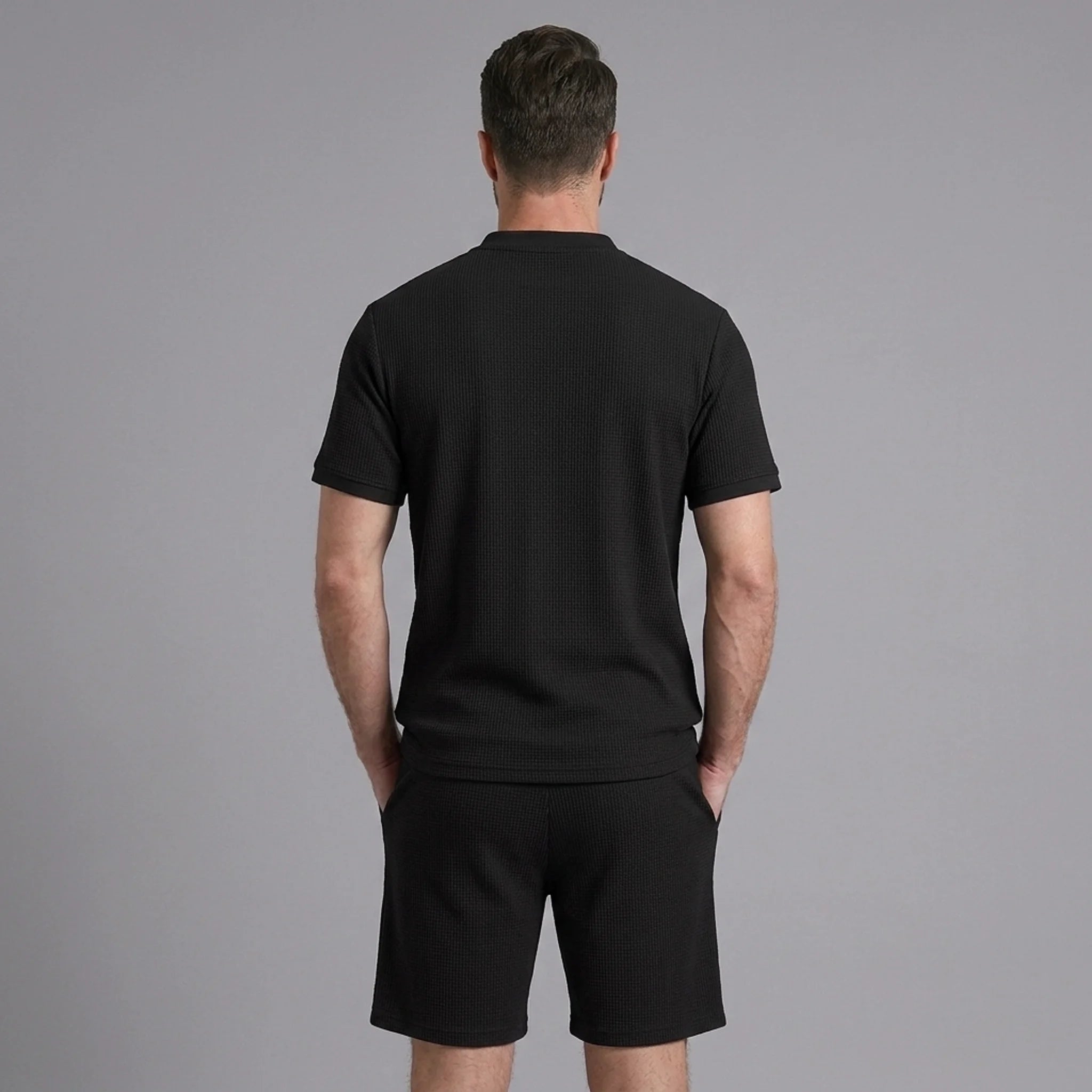 Back view of man wearing black waffle stand collar shirt and drawstring shorts