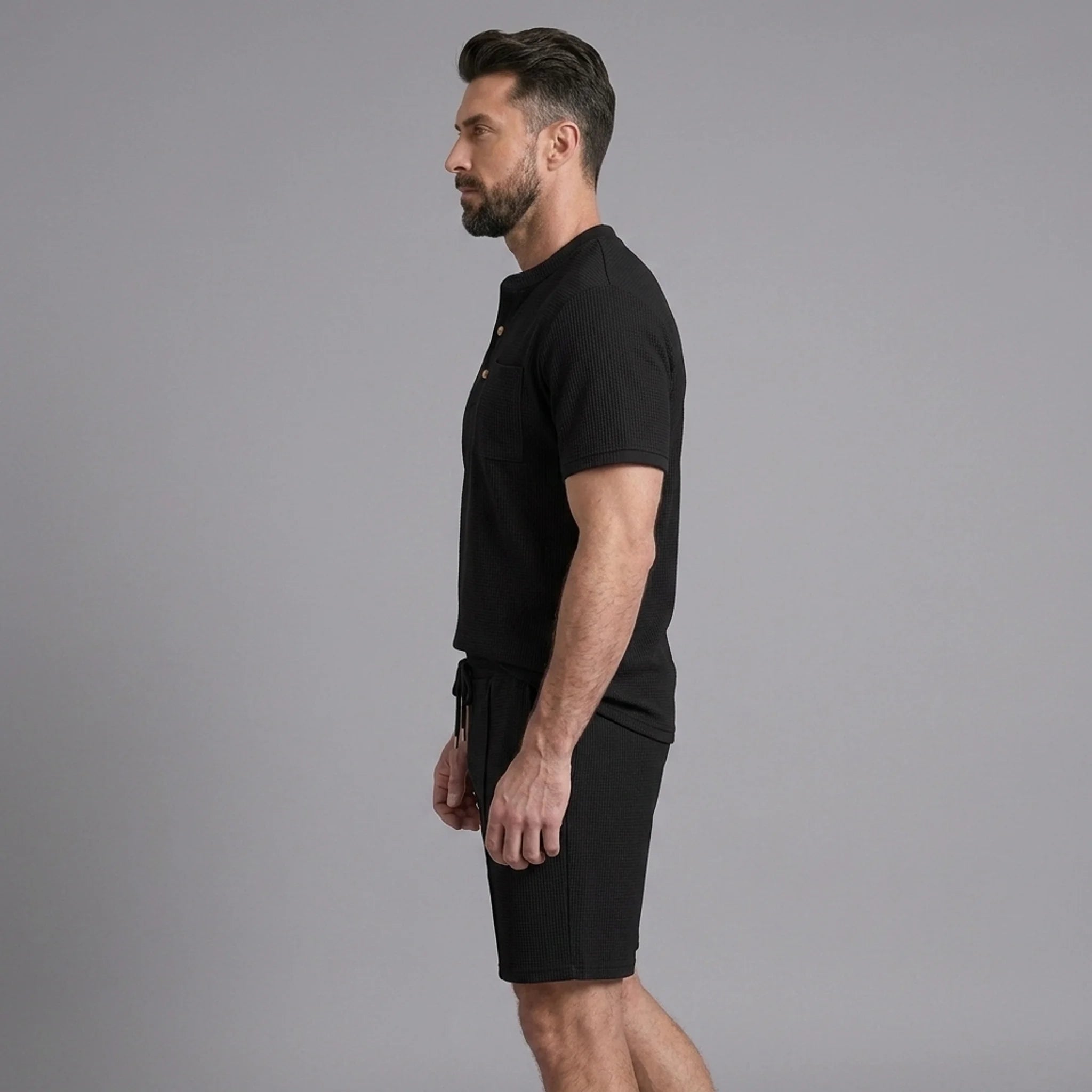 Side view of man in black waffle stand collar button up shirt and drawstring shorts