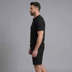 Side view of man in black waffle stand collar button up shirt and drawstring shorts