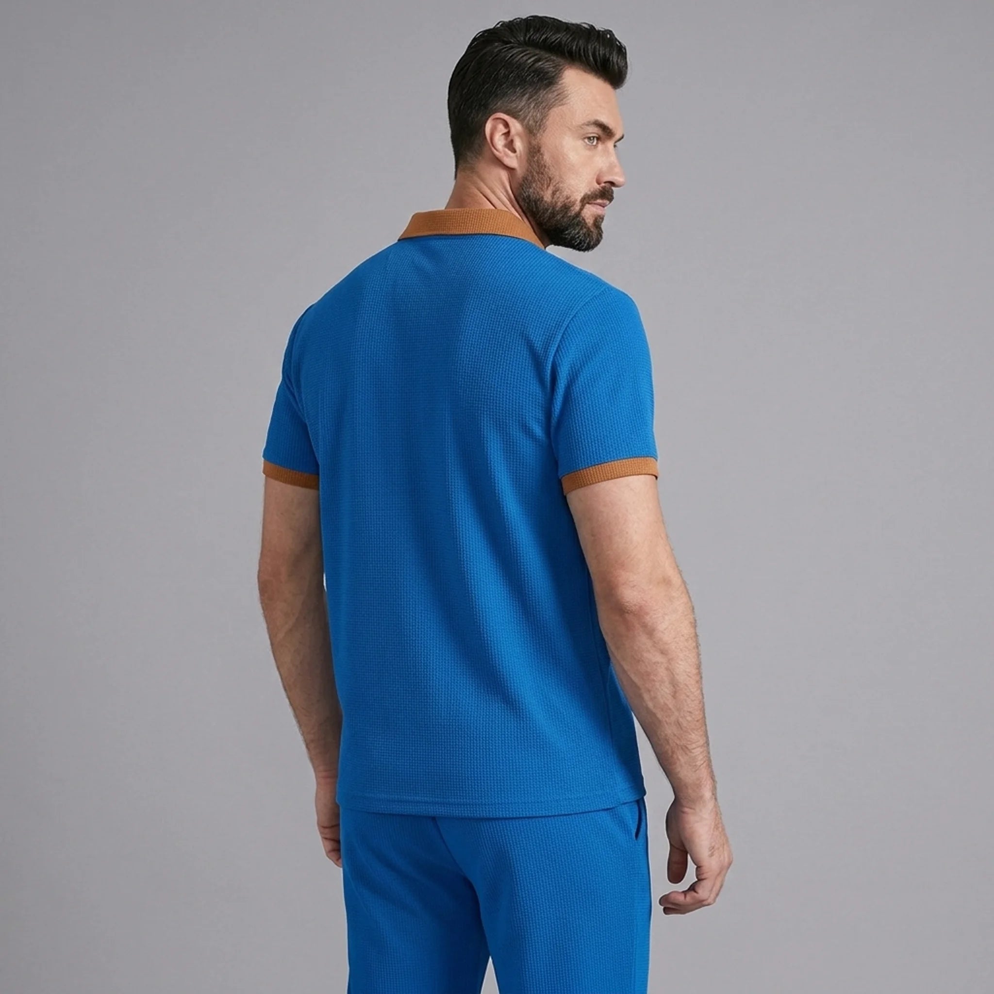 Man wearing blue color block waffle polo and straight leg pants in outdoor lifestyle setting