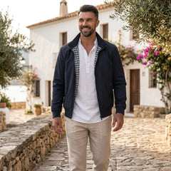 Man wearing MannerCo blue solid bomber jacket in outdoor lifestyle setting