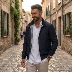 Man wearing MannerCo blue solid bomber jacket in outdoor lifestyle setting