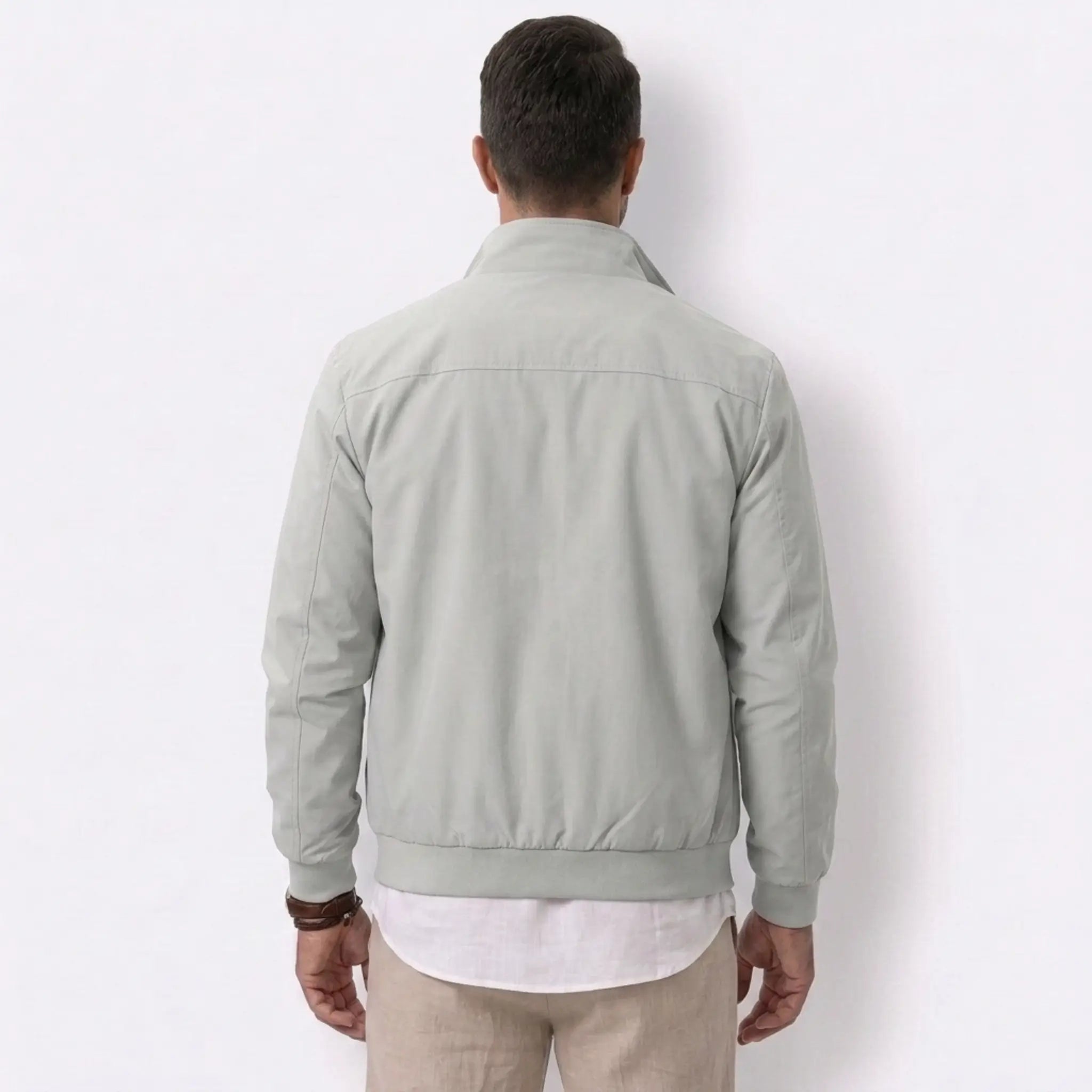 Man wearing MannerCo gray solid bomber jacket with stand collar, side view on plain background