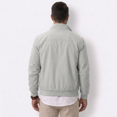 Man wearing MannerCo gray solid bomber jacket with stand collar, side view on plain background
