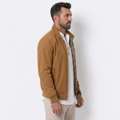 Man wearing MannerCo khaki solid bomber jacket with stand collar, side view on plain background