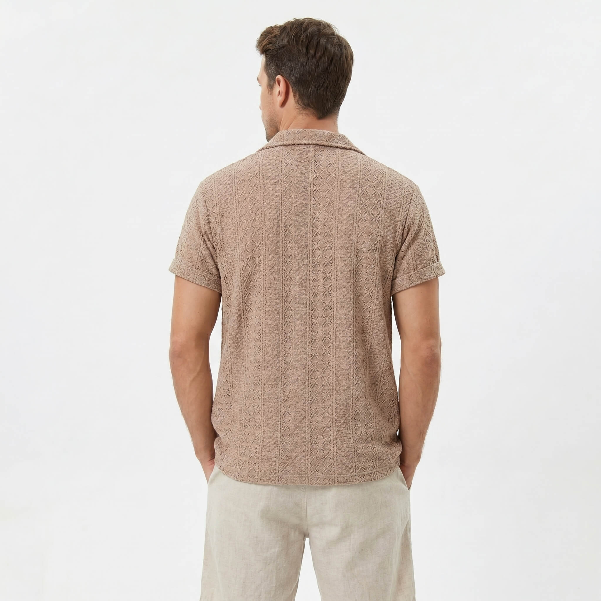 Back view of man wearing coffee brown floral checkerboard jacquard Cuban shirt and linen drawstring shorts