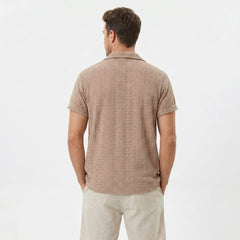Back view of man wearing coffee brown floral checkerboard jacquard Cuban shirt and linen drawstring shorts
